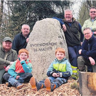 Bereit für die «Staudenschlacht» - Die OK-Mitglieder vor dem frisch polierten Gedenkstein (von links): Janis Huggel, Heinz Huggel, Silvio Beyli, René Hofmann und Stefan Hausherr; vorne: Elio und Flavio (6 und 7 Jahre alt). Bild: zg