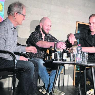Von Waffen und Gewehren - Zum «Villmärgerle» – das Wort ist im Dorf ein Synonym für das Anstossen – braucht es Bier, findet Journalist Samuel Schumacher (rechts) und bringt darum eine Auswahl Villmerger Biere mit, von denen er Moderator Jörg Meier (links) und Schützenkönig Rafael Bereuter gerne eins anbietet. Bild: Chregi Hansen