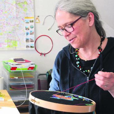 Auf Spurensuche - Esther Amrein bei der Arbeit im Atelier auf dem Oederlin-Areal. Mit Textilkunst beschäftigt sich die Künstlerin schon seit vielen Jahren, den Stickrahmen wird sie nach Berlin mitnehmen. Bild: Chregi Hansen