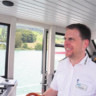 Fahnen hoch bei Sonnenaufgang - Andreas Kneubühl steuert das Schiff sicher. Bei Wind, wie an diesem Tag, bedeutet dies, die Anfahrt an den jeweiligen Steg neu zu beurteilen. Bilder: vaw
