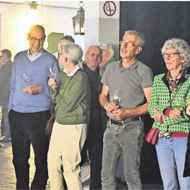 Mit positiver Anspannung - Eine Gruppe von geladenen Gästen begutachten die Anzeigetafel hinter der Bar.