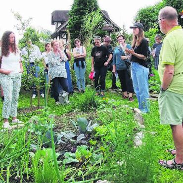 Im Einklang mit der Natur - Im Garten von Judith Goldinger und Esther Brüllhardt lobt Maya Bosshard (mit Dächlikappe) die Vielfalt. Bild: Bernadette Oswald