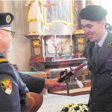 Ernsthaft und mit Humor führen - Leutnant Corsin Wäspi, Samedan, nimmt die Insignien seines militärischen Rangs entgegen, und freut sich sichtlich. Bild: Hans Rechsteiner