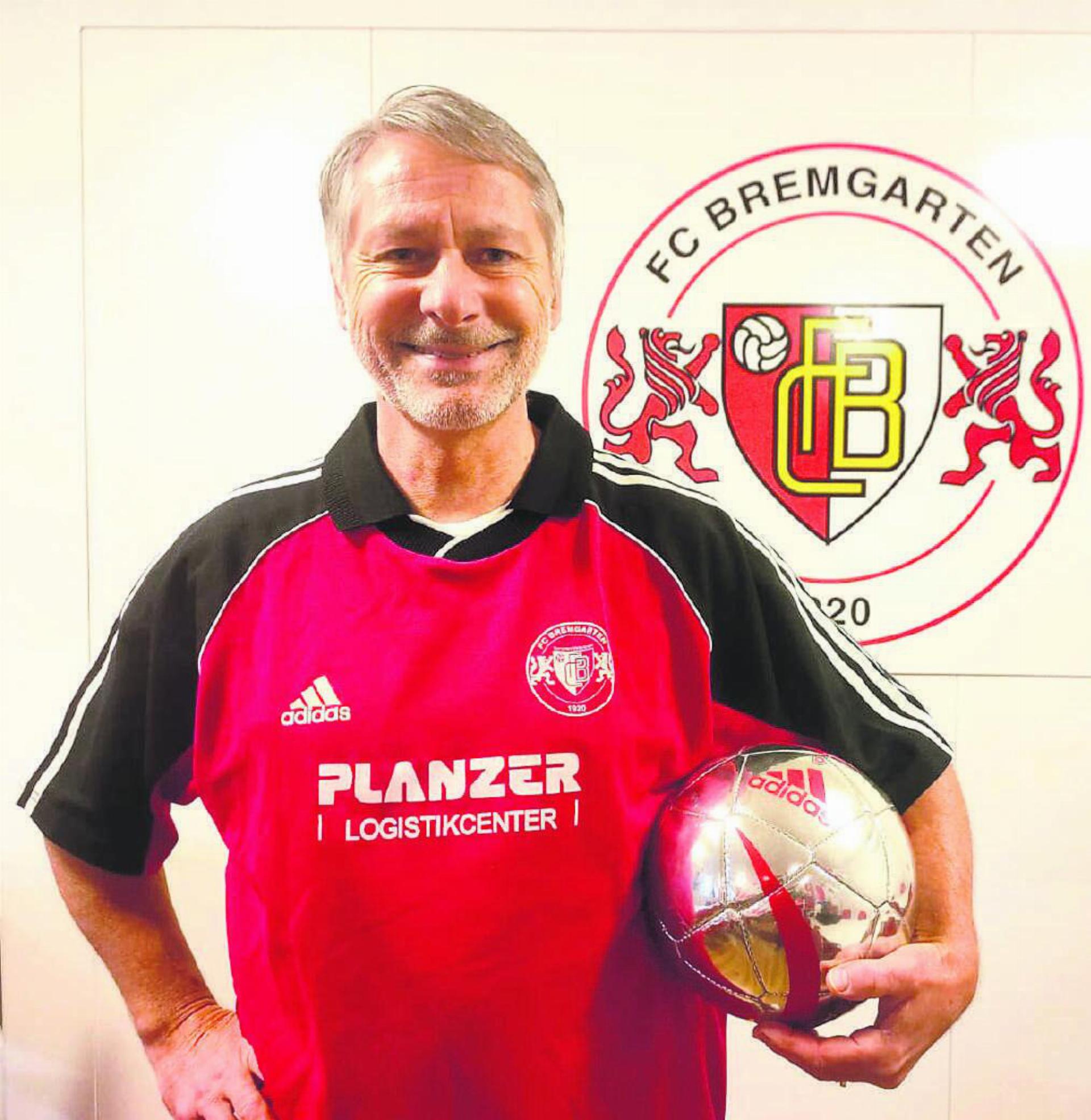 Köbi Beck vor dem Logo «seines» FC Bremgarten. Fast während der Hälfte der 104-jährigen Vereinsgeschichte war der 62-Jährige als aktiver Fussballer mit dabei. Bild: Marco Huwyler