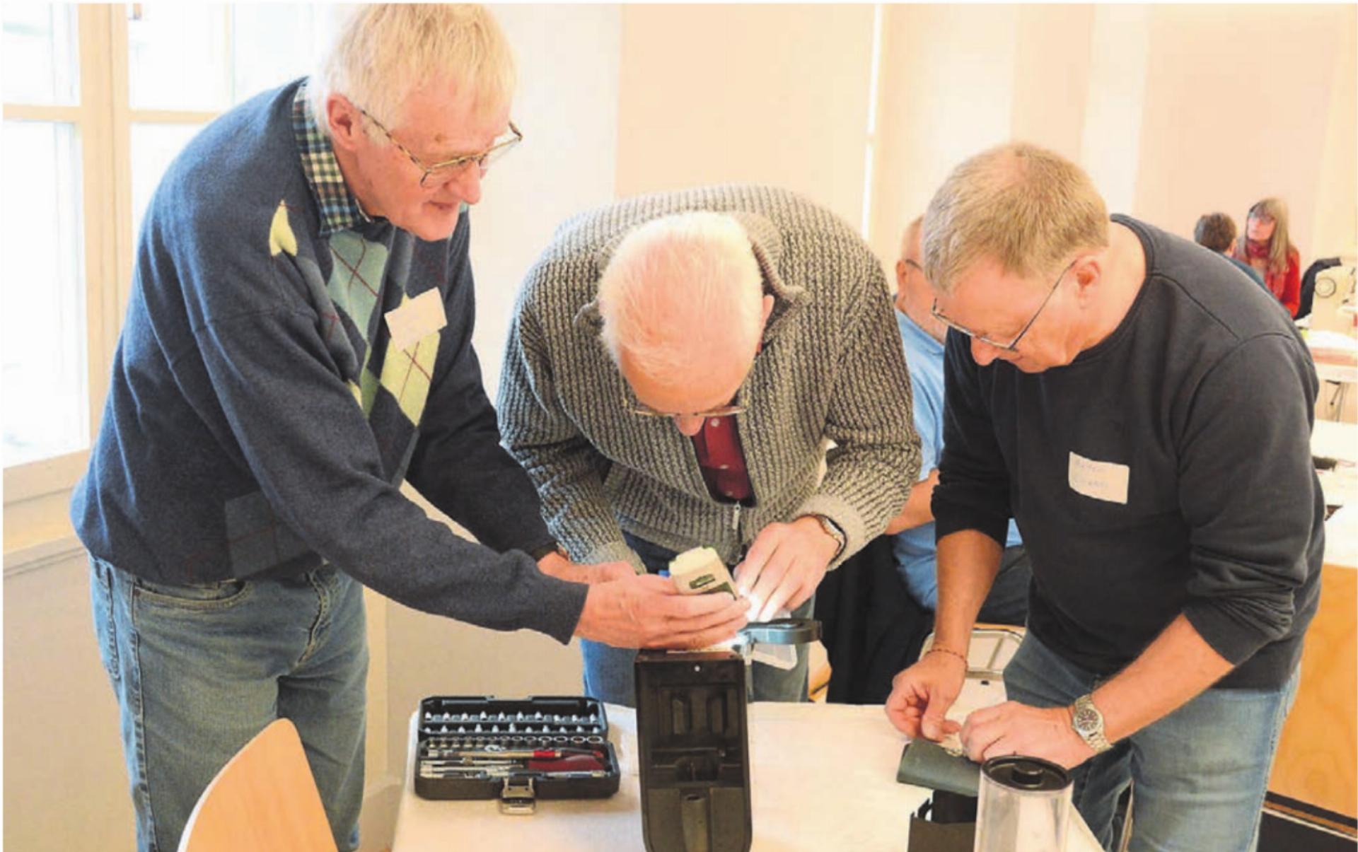 Gleich zu dritt kümmerte sich das Team um die defekte Kaffeemaschine. Dabei wird viel gefachsimpelt. Bilder: Chregi Hansen - Das Bild wird blockiert. – Möglicherweise durch einen aktiven Adblocker.