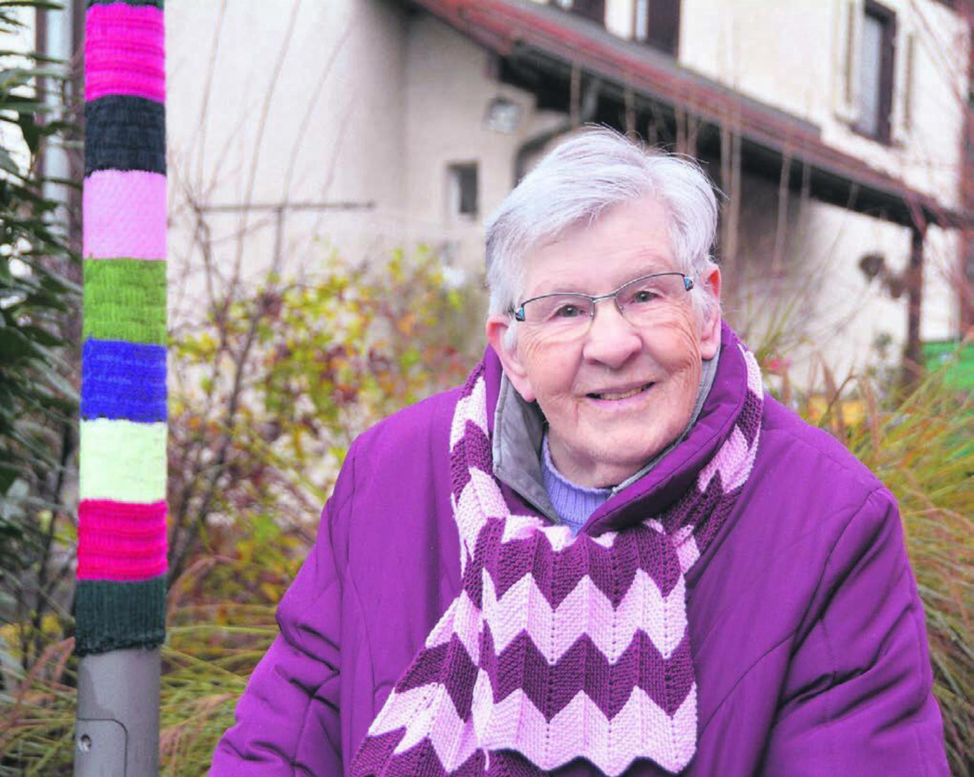 Auch den Schal hat sie selber gestrickt. Lotti Koller neben einem von ihr umstrickten Leuchtkandelaber. Bild: Annemarie Keusch