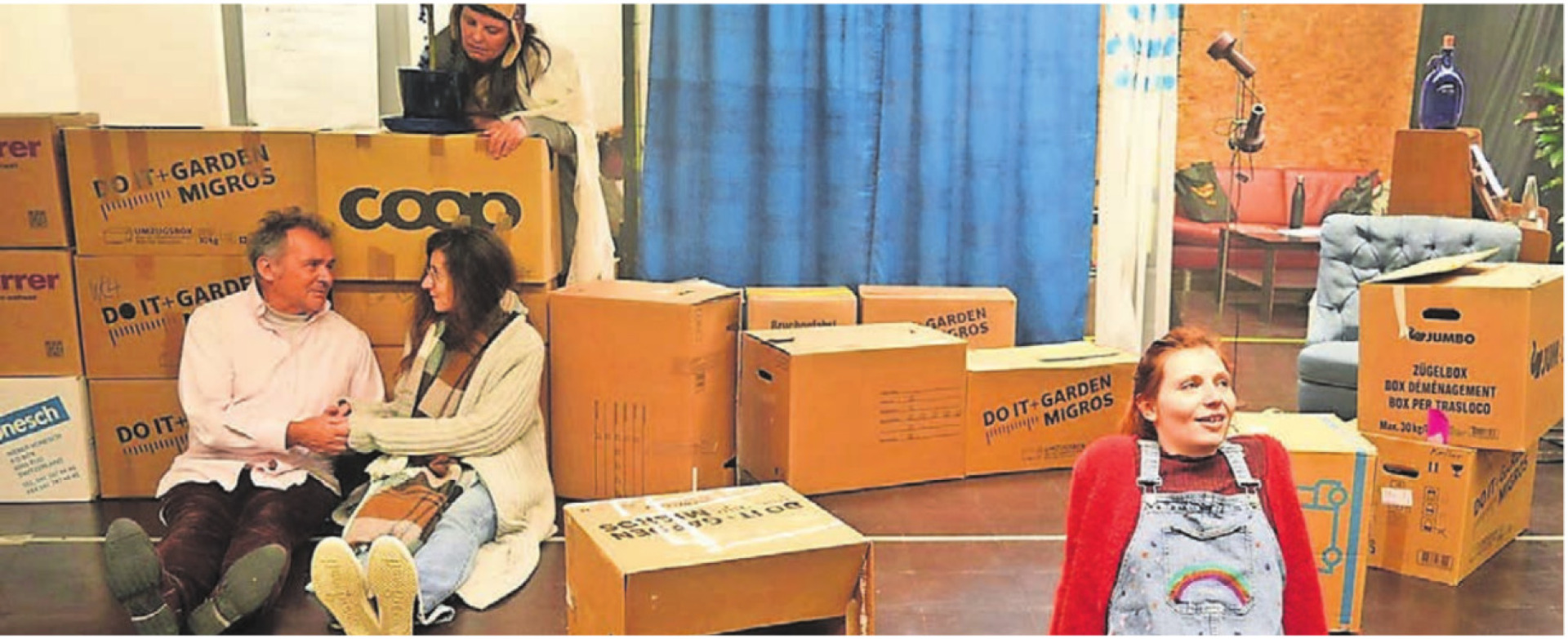 Maxi (Fabienne Bossart, links) im Zügelchaos. Herr Sternheim (Willy Müller) und Frau Lichtblau (Grazia Giamp) haben sich gefunden, beobachtet von Herrn Bello (Irene Kirchmeier). Bild: zg - Das Bild wird blockiert. – Möglicherweise durch einen aktiven Adblocker.