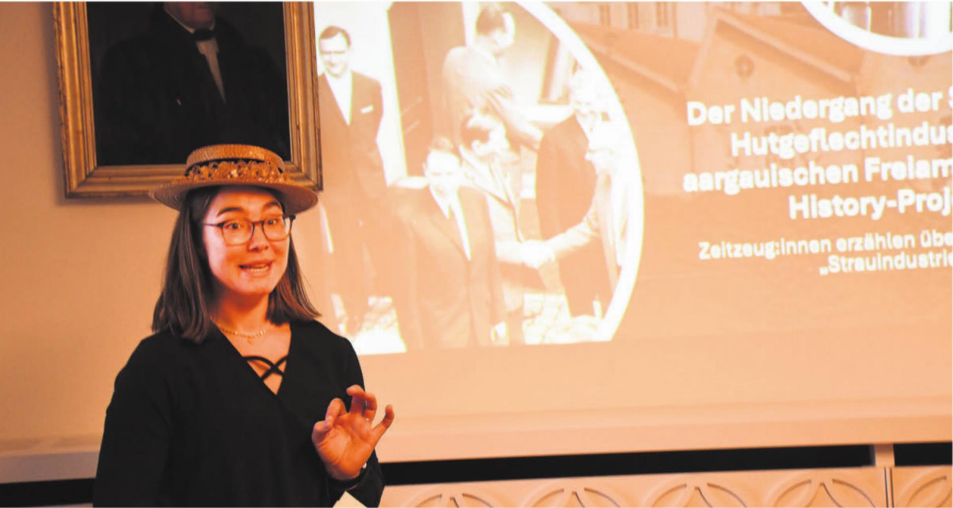 Corina Haller stellte bei ihrem Vortrag der Historischen Gesellschaft Freiamt ihre Masterarbeit vor. Das umfassende Fazit zum Niedergang der Strohindustrie wird dann in der nächsten Jahresschrift der Gesellschaft veröffentlicht. Auf dieser Aufnahme steht sie vor dem Bild, das den Besuch des Bundesrates in Wohlen im Jahr 1966 zeigt.
Bild: Daniel Marti - Das Bild wird blockiert. – Möglicherweise durch einen aktiven Adblocker.