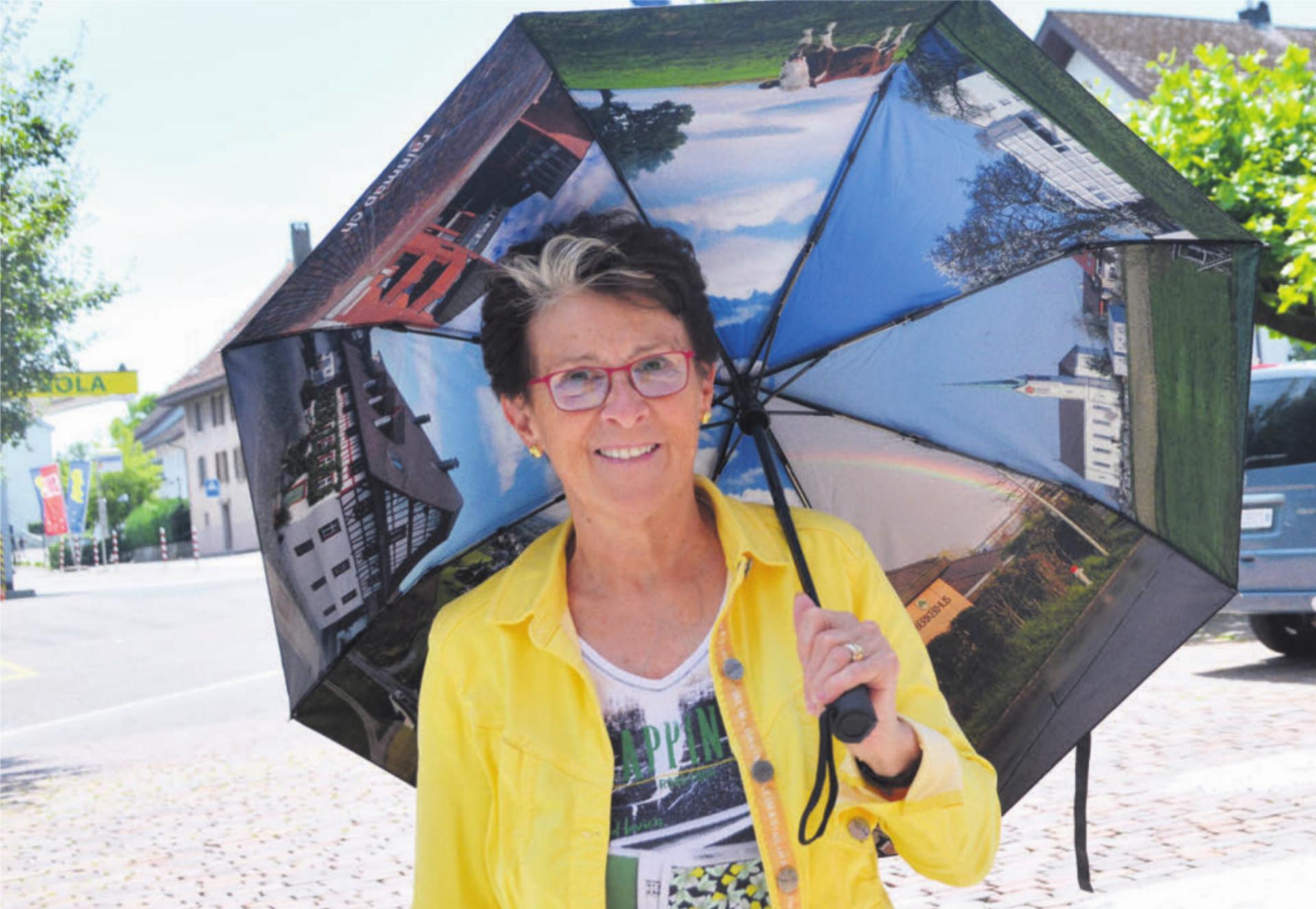 Frau Gemeindeammann Rosmarie Groux zeigt, dass der Regenschirm auch als Schattenspender bei sonnigem Wetter eingesetzt werden kann. Bild: Roger Wetli