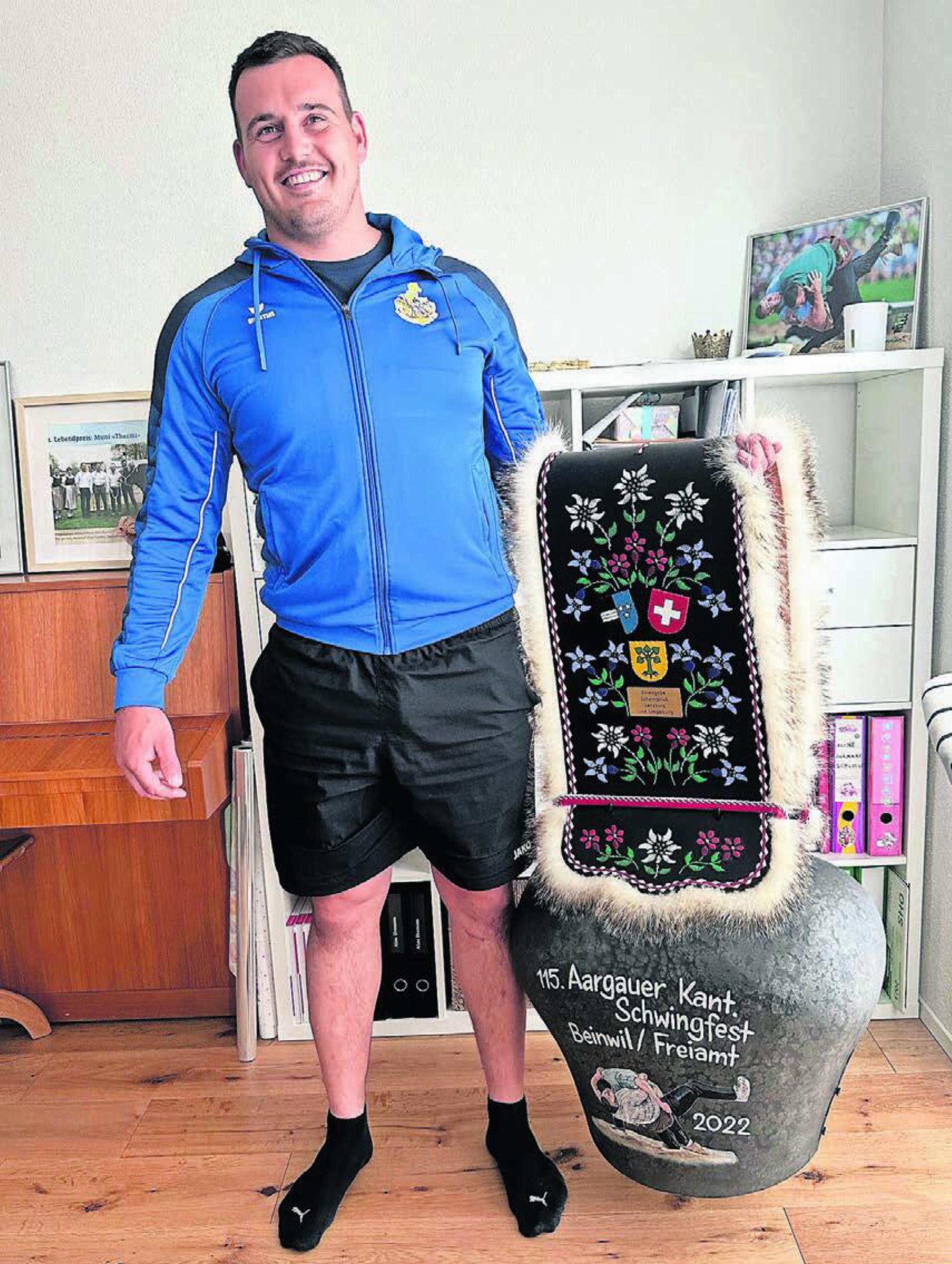 Joel Strebel in seinem Zuhause in Aristau. Er ist 
happy, dass er bald wieder mittun kann –und zeigt 
die Glocke, die er am Aargauer Kantonalschwingfest 2022 in Beinwil/Freiamt holte. 
Bild: Stefan Sprenger