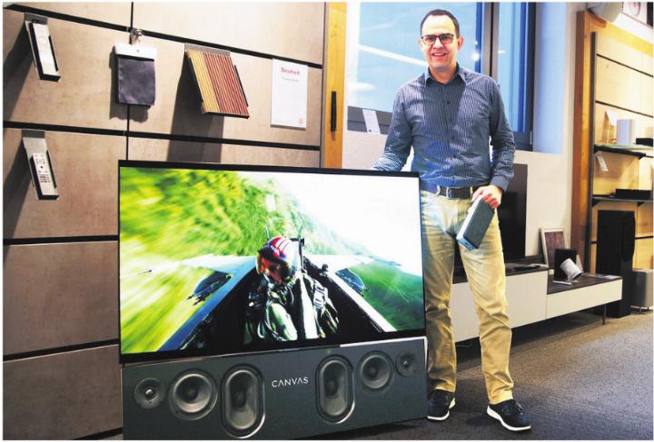 Serge Müller, Geschäftsführer von Tschachtli Klang & Bild, demonstriert im Showroom an der Breitistrasse 6 in Wohlen die CANVAS HiFi Soundbar (unterhalb des Bildschirms) sowie in der linken Hand den kabellosen Sprachverstärker OSKAR, der flexibel in der ganzen Wohnung einsetzbar ist. Bild: zg
