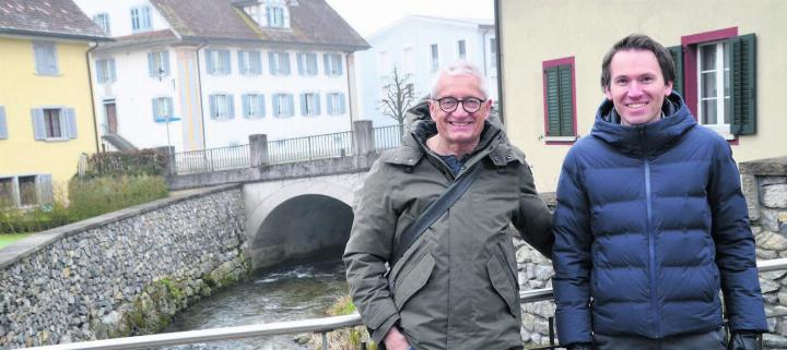 Mit dem Hochwasserschutz fand auch eine optische Aufwertung statt. Gemeinderat Luigi Alberti und Gemeindeschreiber Lorenz Staubli (von links) vor den Natursteinmauern, mit denen der Jonenbach zwischen Sennhütten- und Staldenstrasse eingerahmt wurde. Bilder: Thomas Stöckli / zg