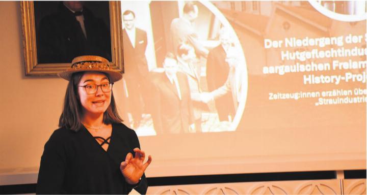 Corina Haller stellte bei ihrem Vortrag der Historischen Gesellschaft Freiamt ihre Masterarbeit vor. Das umfassende Fazit zum Niedergang der Strohindustrie wird dann in der nächsten Jahresschrift der Gesellschaft veröffentlicht. Auf dieser Aufnahme steht sie vor dem Bild, das den Besuch des Bundesrates in Wohlen im Jahr 1966 zeigt.
Bild: Daniel Marti